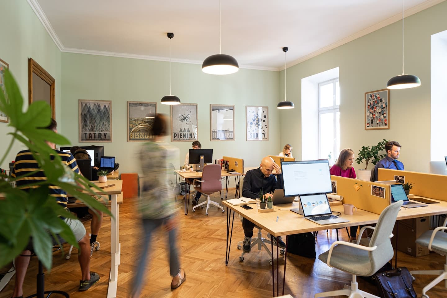Professionals work on laptops at desks in a bright open-plan office.